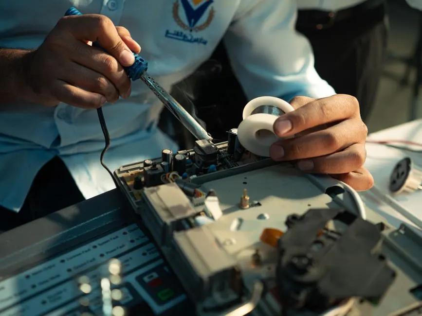 Detailed view of hands soldering an electronic circuit board, showcasing technical skill.